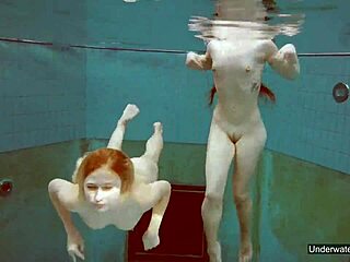 Dua gadis menawan berenang di kolam renang dan bermain dengan tubuh mereka