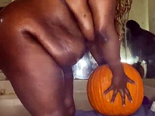 Black babe enjoys Halloween with dildo and pumpkin riding